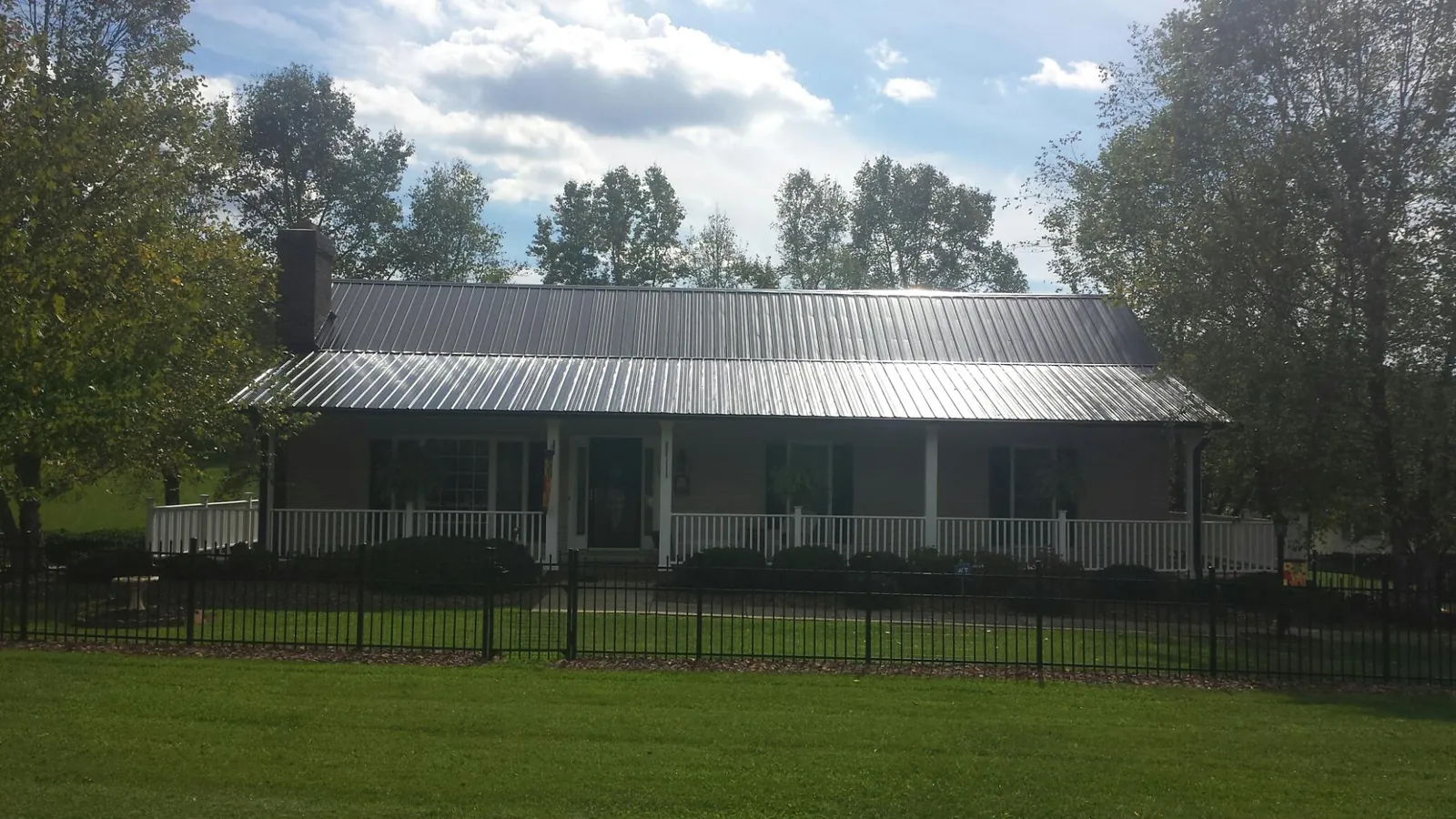Gray metal roof on a brick ranch with a full width front porch — Gutter Guard Installation work by our crew in Pineville